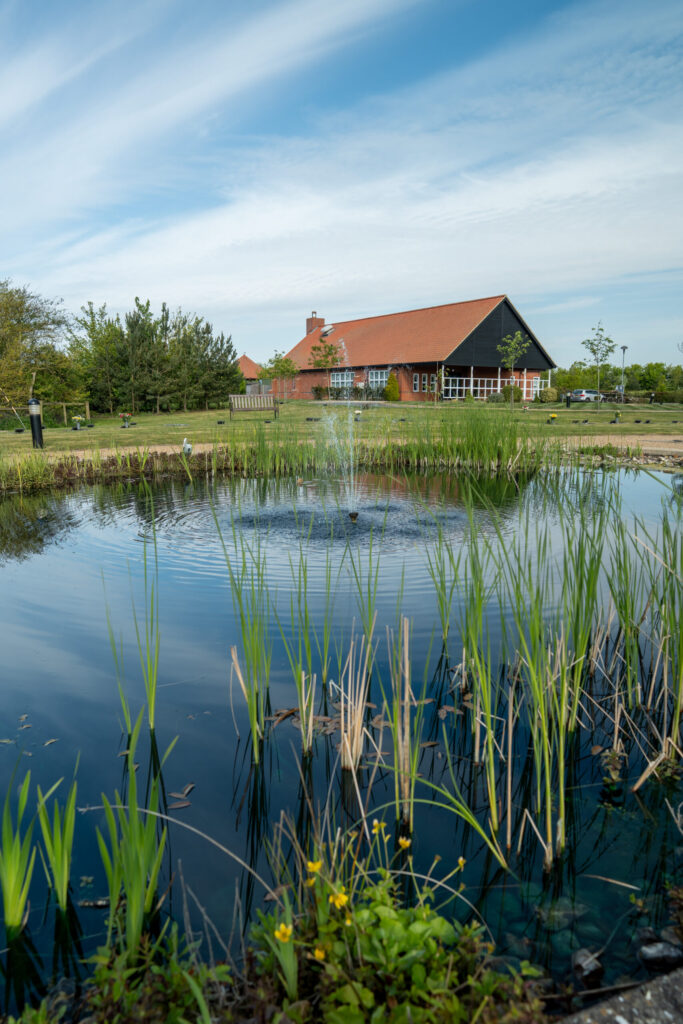 Reed-lined fountain pond with the crematorium building beyond