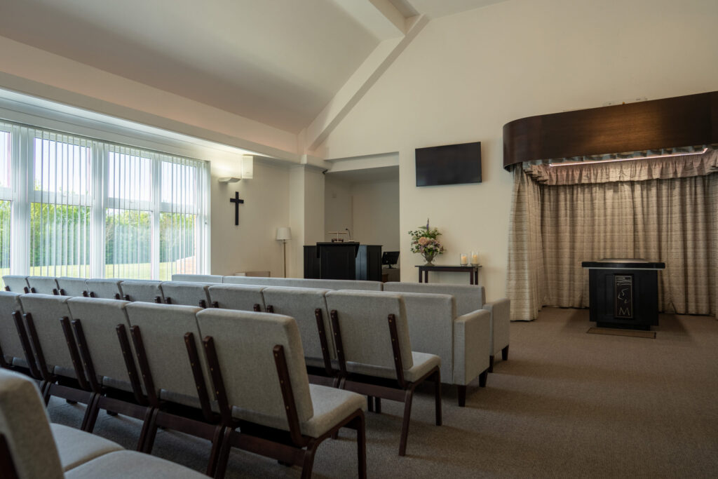 Interior of the crematorium chapel with seating facing the catafalque and curtains